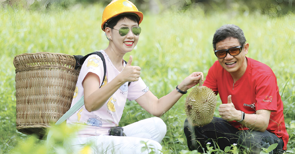 A women and men sitting on ground and picking durian