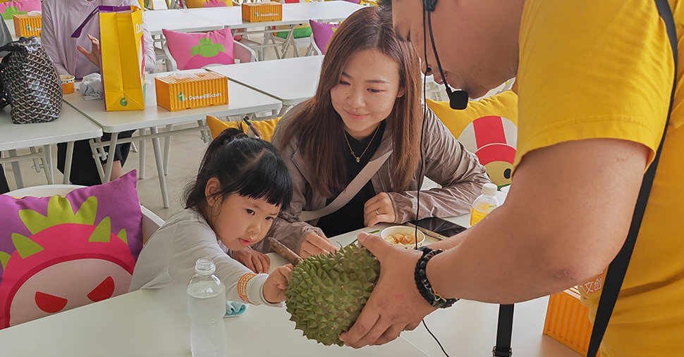 A girl and a women, the girl touching durian