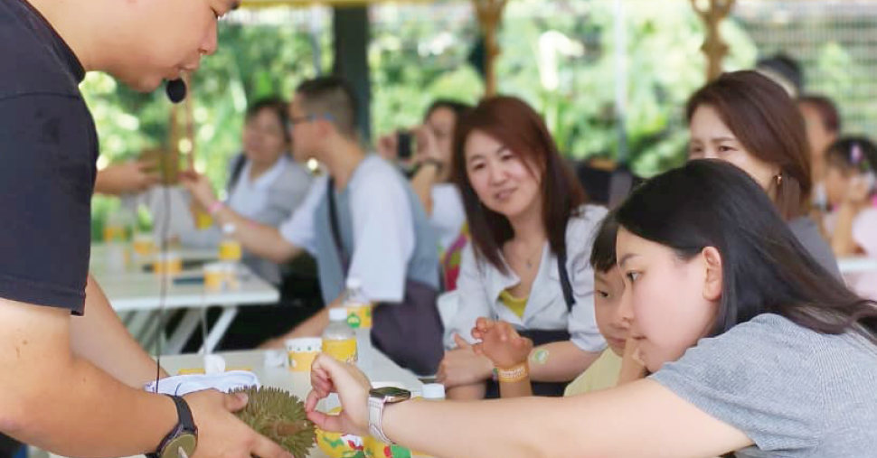 A man holding a durian let a woman touch it