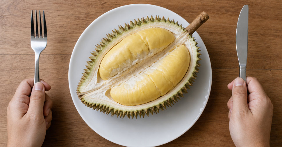 Hands holding knife and fork, a durian on a plate