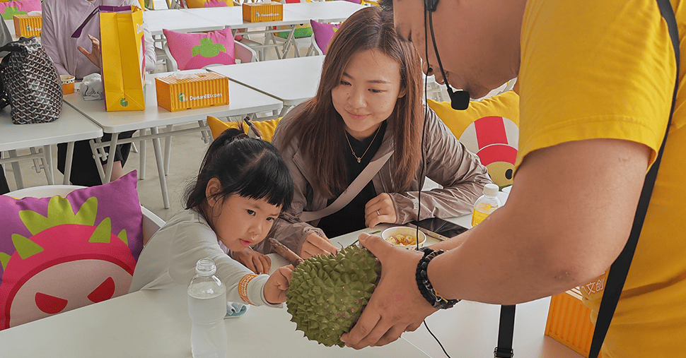 A girl sit with mother and touching durian